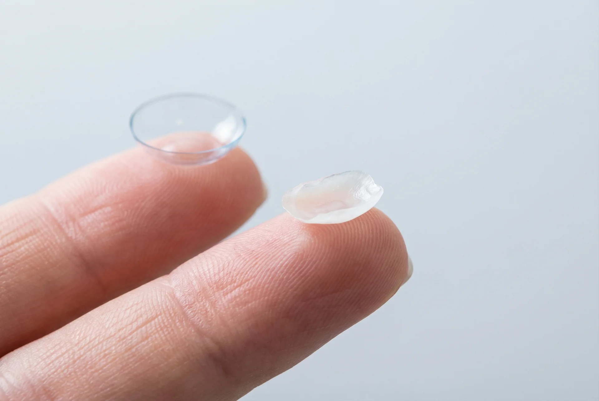 Facette en céramique tenue entre deux doigts, montrant son épaisseur ultra-fine comparable à une lentille de contact